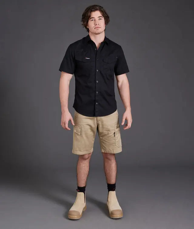 Man wearing a black shirt and beige shorts against a gray background