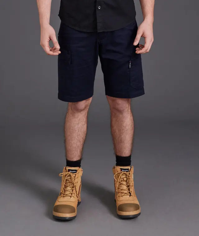 Person wearing navy shorts and tan boots on a gray background