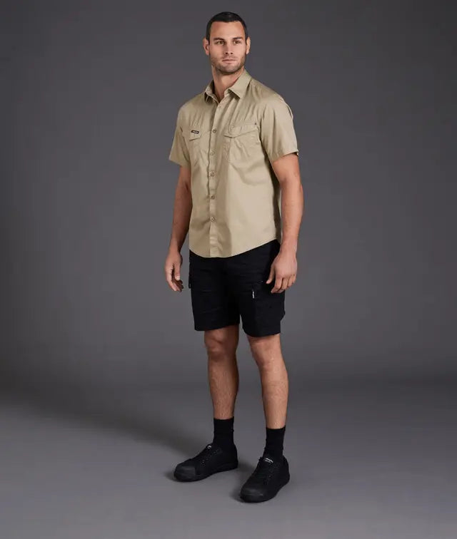 Man wearing a beige shirt and black shorts on a gray background
